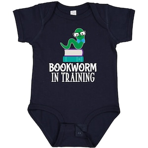 May include: Navy blue baby bodysuit with the text "BOOKWORM IN TRAINING". The design features a green worm wearing glasses and a bow tie, sitting atop a stack of books. A cute and educational design for infants.