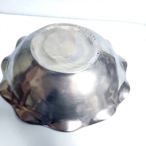 Peut inclure: Un bol en m&eacute;tal argent&eacute; avec un bord festonn&eacute;. Le bol est vide et a une surface brillante et r&eacute;fl&eacute;chissante.