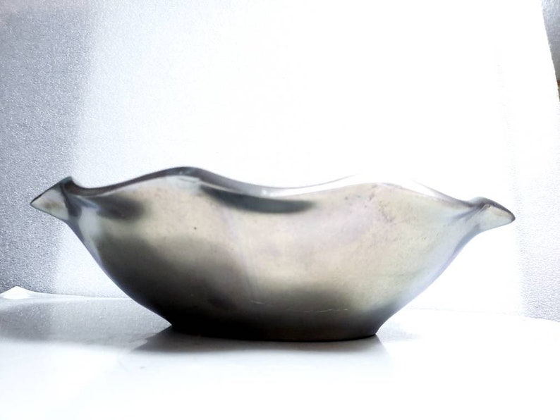 Peut inclure: Un bol en c&eacute;ramique ondul&eacute; de couleur argent&eacute;e avec une surface lisse et r&eacute;fl&eacute;chissante.