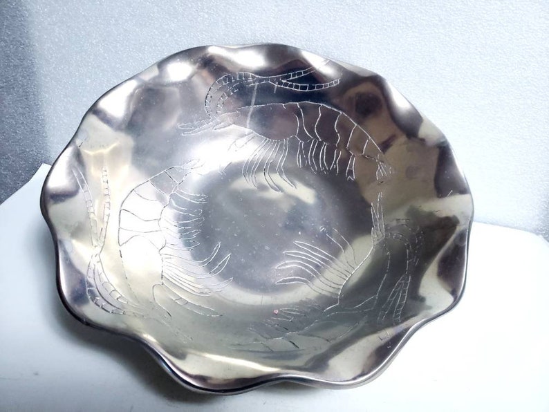 Peut inclure: Un bol en argent avec un bord festonn&eacute; et un motif en relief de crevettes. Le bol est en m&eacute;tal et a une finition brillante.