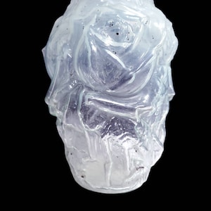 May include: A clear glass vase with a textured surface, featuring a raised design of a rose.