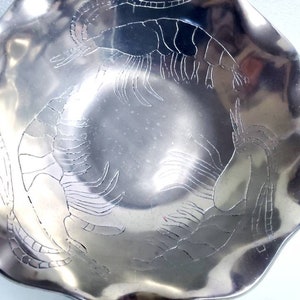 Peut inclure: Un bol en m&eacute;tal argent&eacute; avec un bord festonn&eacute; et un motif grav&eacute; de quatre crevettes.