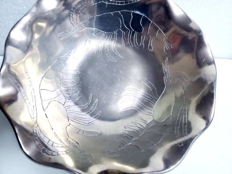 Peut inclure: Un bol en m&eacute;tal argent&eacute; avec un bord festonn&eacute; et un motif grav&eacute; de quatre crevettes.