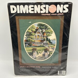 May include: A Dimensions counted cross stitch kit titled Lovely Victorian Home, featuring a house illustration within an oval mat. The package includes cotton thread, 14 count ivory Aida, needle, and instructions for a 15 by 18 inch frame size.