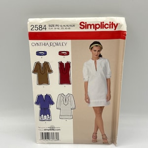 May include: A Simplicity sewing pattern envelope, number 2584, featuring Cynthia Rowley designs. The front displays a white tunic dress, illustrations of four variations in brown, red, blue, and white, and size information for P5 12, 14, 16, 18, 20.