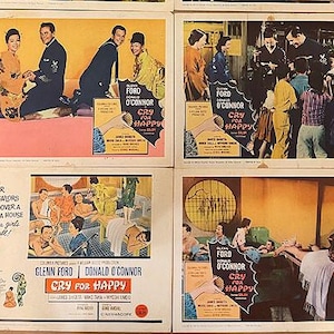 May include: A collection of eight vintage movie lobby cards for "Cry for Happy" starring Glenn Ford and Donald O'Connor. The cards feature scenes with actors in various settings, including a geisha house.