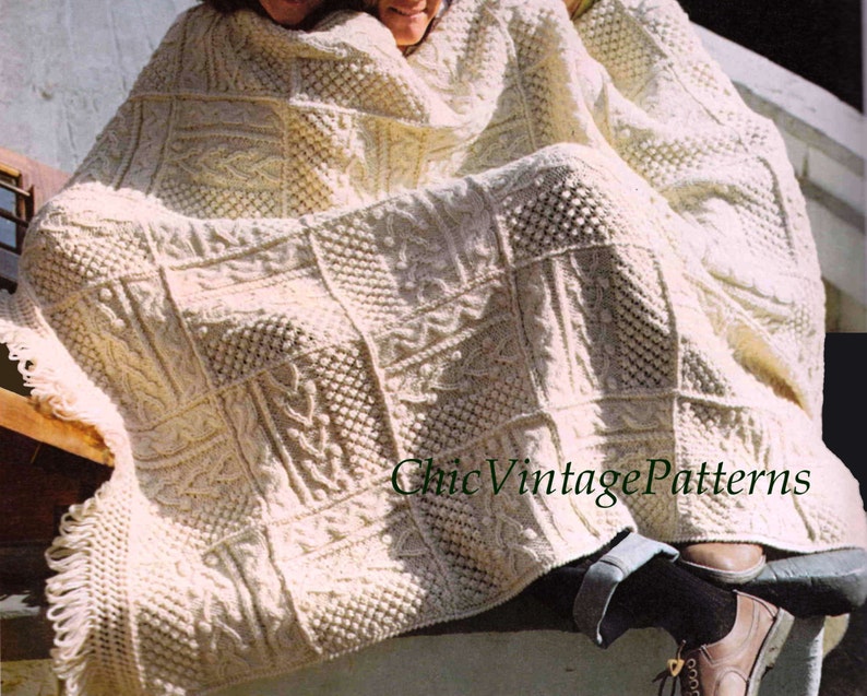Pode incluir: Cobertor de malha creme com uma variedade de padr&otilde;es quadrados texturizados. O cobertor tem uma borda com franjas e est&aacute; sobre algu&eacute;m. O texto "Chic Vintage Patterns" &eacute; vis&iacute;vel.