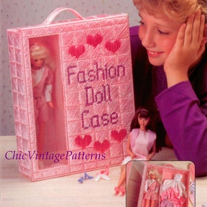 May include: A pink, handmade "Fashion Doll Case" with a handle, featuring a grid pattern and embroidered hearts. The case holds a doll in a pink outfit. The text "Fashion Doll Case" is embroidered on the front.