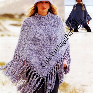 Könnte beinhalten: Eine Frau trägt einen blau-weiß gestrickten Poncho mit Fransen. Sie trägt auch einen passenden blauen Hut. Der Poncho hat einen hohen Kragen und ein strukturiertes Aussehen. Das Bild ist im Freien aufgenommen.