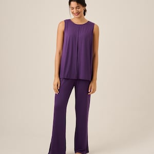 May include: A sleeveless, purple pajama set. The top has a round neckline and a vertical seam down the front. The pants are wide-legged. The set is made of a soft, flowing fabric.