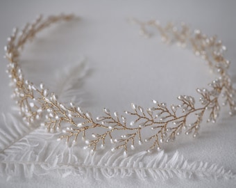 May include: A delicate gold headband with small white pearls arranged in a leafy pattern.