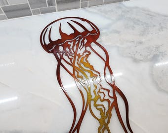 May include: A metal wall decor in the shape of a jellyfish with a red, orange, and yellow gradient. The jellyfish is on a white marble background.
