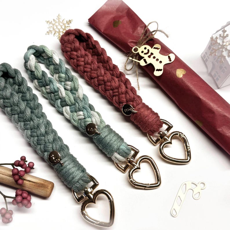 May include: Three braided macrame wristlets with gold-toned heart-shaped lobster clasps. One is solid dark green, one is a variegated mix of sage green and white, and one is solid deep red. Each features a small circular metal charm attached.