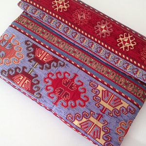 May include: A purple and red patterned laptop sleeve with a geometric design. The sleeve is made of a soft, woven fabric.