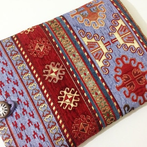 May include: A blue and red patterned fabric laptop sleeve with a button closure.