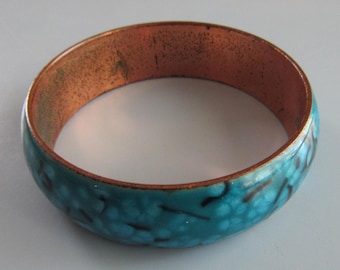Puede incluir: Un brazalete turquesa con interior de cobre y un patrón moteado blanco.
