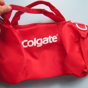 May include: Red travel bag with white handles and a white "Colgate" logo.