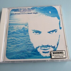 May include: A CD case with a blue and white design featuring a silhouette of a man's face. The text on the case reads "paulmac 3000 feet high" and "WARNING: This recording contains explicit language".