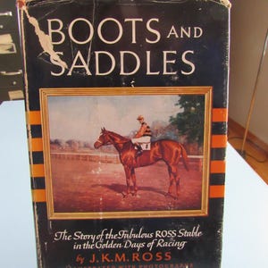 May include: Vintage book titled "BOOTS AND SADDLES" with a black cover and white lettering. The cover features an illustration of a horse and rider in a race. The book's title is above the illustration, and the author's name is below.