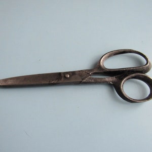 May include: A pair of vintage metal scissors with a silver finish. The scissors have a simple design with rounded handles.