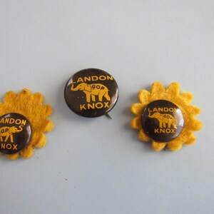 May include: Three vintage political campaign buttons. The buttons are dark brown with yellow text and an elephant graphic. Two buttons are attached to yellow felt flower shapes. The text on the buttons reads "LANDON GOP KNOX".