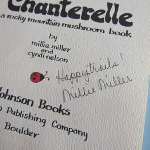 May include: Close-up of a book cover titled "Chanterelle," a rocky mountain mushroom book. The cover features text, including the authors' names, and a handwritten note with a ladybug illustration. Published by Johnson Books.