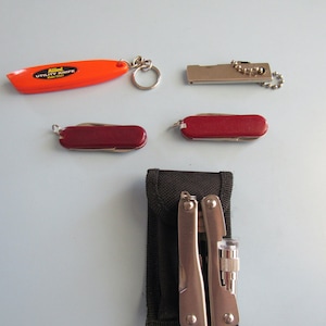 May include: A set of five tools including a red utility knife, two small red pocket knives, a silver multi-tool with a flashlight, and a black pouch.
