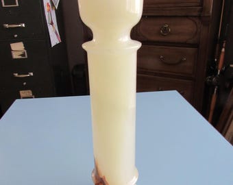 May include: A tall, white marble candle holder with a wide base and a narrow top. The holder has a light brown and orange swirl pattern.
