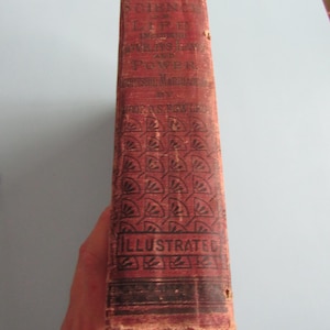 May include: A vintage book spine with the title "Science of Life" and the word "Illustrated" in red and black lettering. The book's cover is a faded red with a repeating geometric pattern.
