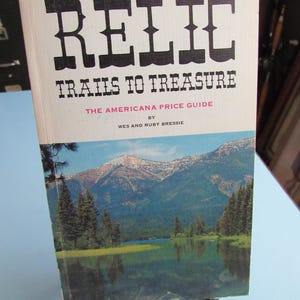 May include: A book titled "Relic Trails to Treasure: The Americana Price Guide by Wes and Ruby Bressie". The cover features a scenic landscape with a lake and mountains.