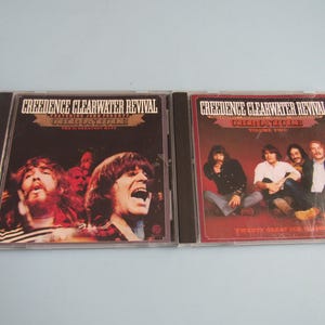 May include: Two Creedence Clearwater Revival music CDs in plastic cases. The left cover features band members with the text Chronicle The 20 Greatest Hits. The right cover shows four band members with the text Chronicle Volume Two Twenty Great CCR Classics.