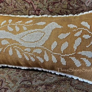 May include: Mustard-colored rectangular pillow with a white embroidered bird and leaf design. The pillow has a white fringe border and the text "ThreeSheepStudio.com" is visible on the bottom right.