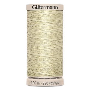 May include: A spool of Gütermann thread in a light beige color. The spool has a white top and bottom with the brand name "Gütermann" printed on the top. The bottom of the spool has the text "200 m - 220 yds/vgs".