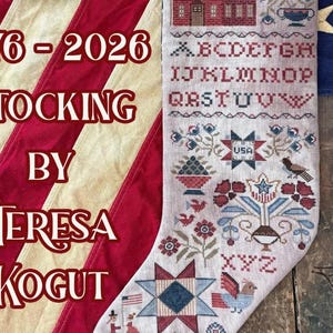 May include: A handcrafted Christmas stocking with a patriotic theme. The stocking features cross-stitch embroidery with a house, alphabet, stars, and floral designs in red, blue, and white. The text "1776-2026 STOCKING BY TERESA KOGUT" is displayed.