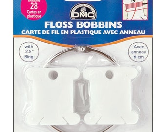 May include: A package of 28 white plastic floss bobbins with a 2.5 inch ring. The package is labeled "Floss Bobbins Carte de Fil en Plastique Avec Anneau" and features the DMC logo.