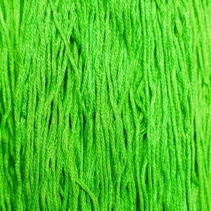 May include: Close-up of bright green yarn, tightly wound and textured. The yarn appears to be made of multiple strands, creating a dense, vibrant surface. The color is a vivid, almost neon green, suggesting a textile craft material.