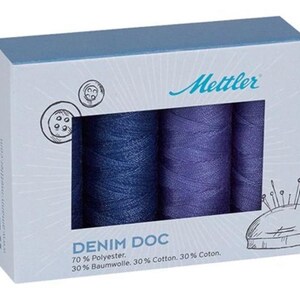 May include: A box set of Mettler Denim Doc thread spools in shades of blue and purple. The box features a drawing of buttons and a pin cushion. The text "DENIM DOC" and thread composition are printed on the box.