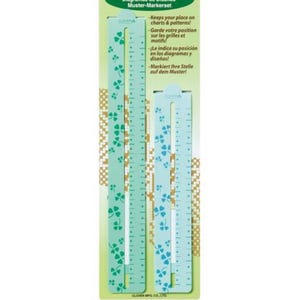 May include: A set of two mint green chart markers with a clover pattern. The markers have a ruler design with measurements and text in multiple languages. The packaging includes the text "Keeps your place on charts & patterns!"