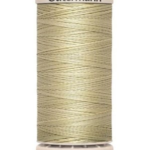 May include: A spool of Gutermann thread in a pale olive green color. The thread is tightly wound around a cylindrical core, with the brand name visible at the top. The thread is designed for sewing and crafting projects.
