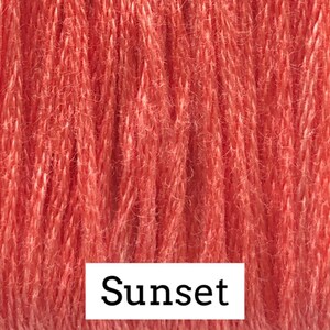 May include: Close-up of a skein of yarn in a vibrant sunset orange color. The yarn has a textured appearance, with visible fibers and a slightly fuzzy surface. The word "Sunset" is displayed in a white rectangular box at the bottom of the image.