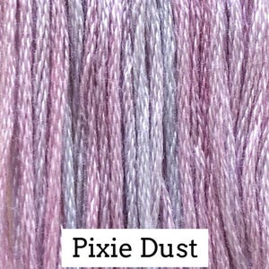 May include: Close-up of a bundle of Pixie Dust colored embroidery floss. The floss is a blend of pink, lavender, and white threads, creating a soft, textured appearance. The text "Pixie Dust" is displayed in a white rectangle at the bottom of the image.