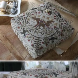 May include: A square cushion with detailed embroidery. The design includes two birds, floral patterns, and the text "United We Stand" and "Blackbird Designs". The colour scheme features beige, brown, and red accents, creating a vintage aesthetic.