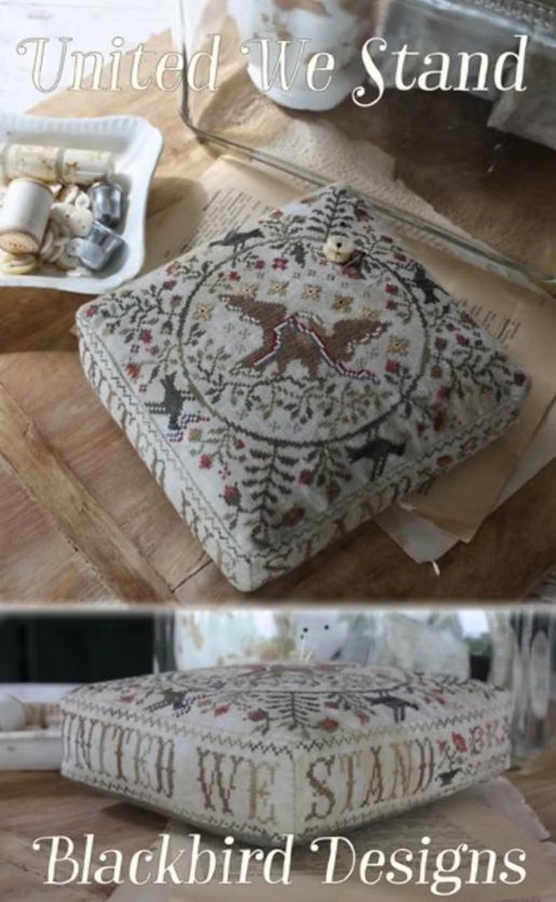 May include: A square cushion with detailed embroidery. The design includes two birds, floral patterns, and the text "United We Stand" and "Blackbird Designs". The colour scheme features beige, brown, and red accents, creating a vintage aesthetic.