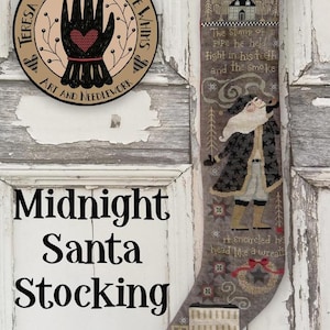 May include: A decorative Christmas stocking with a Santa Claus design. The stocking is gray with a detailed illustration of Santa smoking a pipe, with text that reads "Midnight Santa Stocking". The stocking is decorated with stars and a wreath.