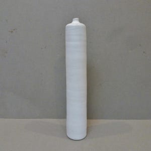 Può includere: Un vaso alto in ceramica bianca con una forma cilindrica liscia.