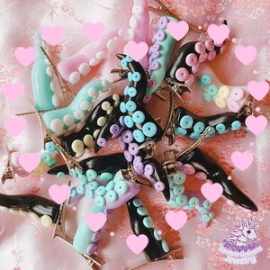 May include: A collection of colourful octopus hair clips. The clips are made of polymer clay and feature a variety of colours, including pink, blue, purple, and black. The clips are shaped like octopus tentacles and have small, round suction cups. The clips are perfect for adding a touch of whimsy to any hairstyle.