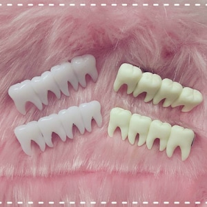 hairclips with four fake teeth in a line, two on each side of the image