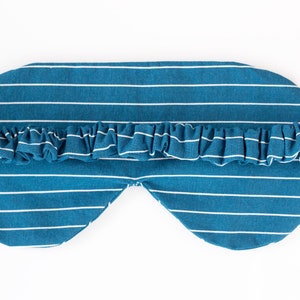 Puede incluir: Una m&aacute;scara para dormir a rayas blancas y azul verdoso con un ribete con volantes. La m&aacute;scara est&aacute; dise&ntilde;ada para cubrir los ojos y tiene un aspecto suave y c&oacute;modo. Las rayas horizontales a&ntilde;aden un toque cl&aacute;sico a este accesorio para dormir.