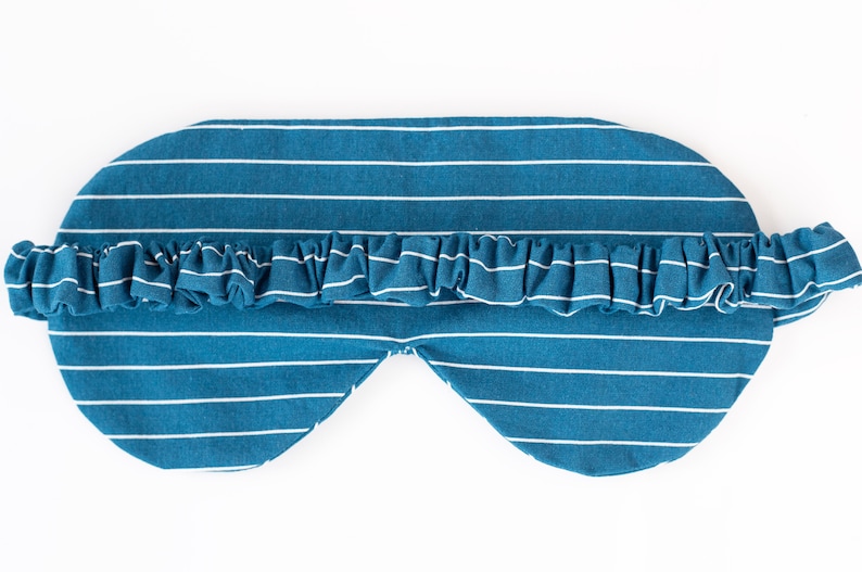 Puede incluir: Una m&aacute;scara para dormir a rayas blancas y azul verdoso con un ribete con volantes. La m&aacute;scara est&aacute; dise&ntilde;ada para cubrir los ojos y tiene un aspecto suave y c&oacute;modo. Las rayas horizontales a&ntilde;aden un toque cl&aacute;sico a este accesorio para dormir.
