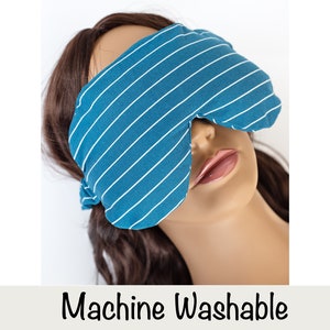 Puede incluir: Una m&aacute;scara para los ojos de color turquesa con rayas blancas es usada por un maniqu&iacute;. La m&aacute;scara est&aacute; hecha de tela suave y est&aacute; dise&ntilde;ada para bloquear la luz. El texto "Machine Washable" se muestra debajo.